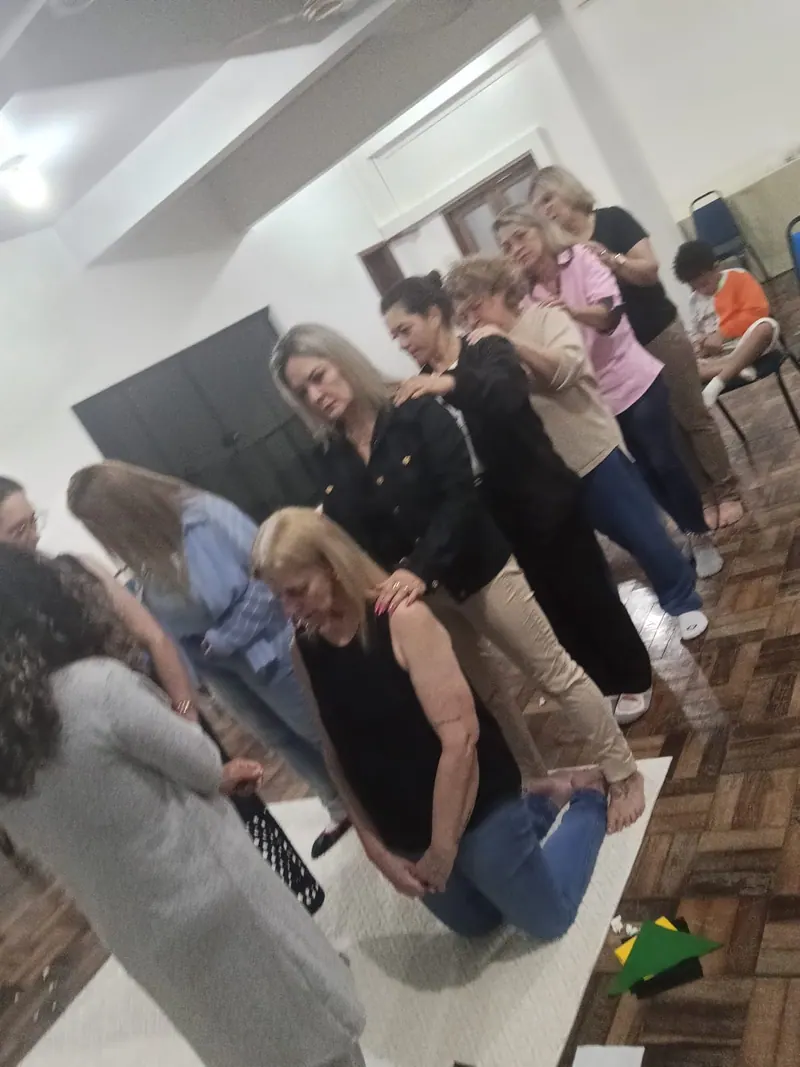 Participantes em fila, com as mãos nos ombros, durante uma constelação